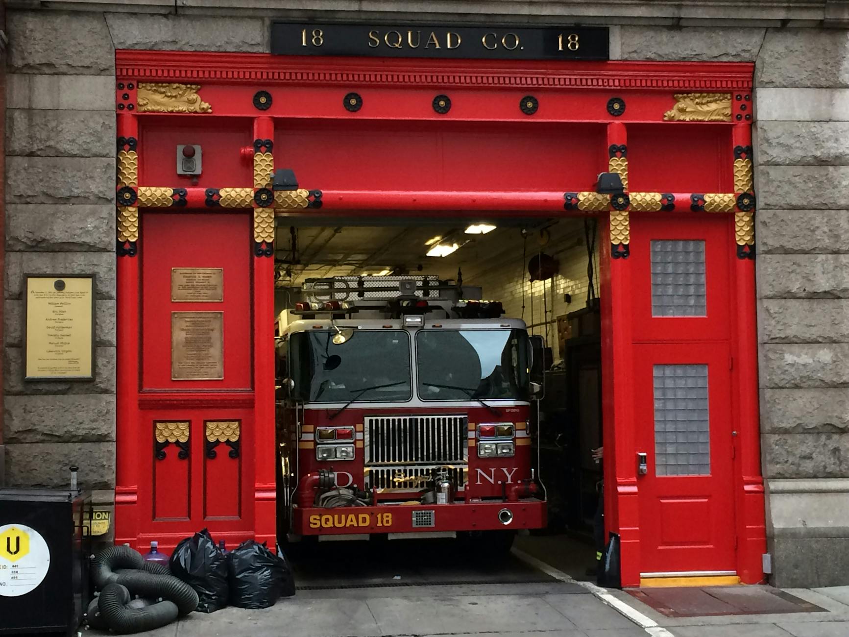 Fire truck in the iconic red door Squad 18 firehouse in NYC, ready for action.