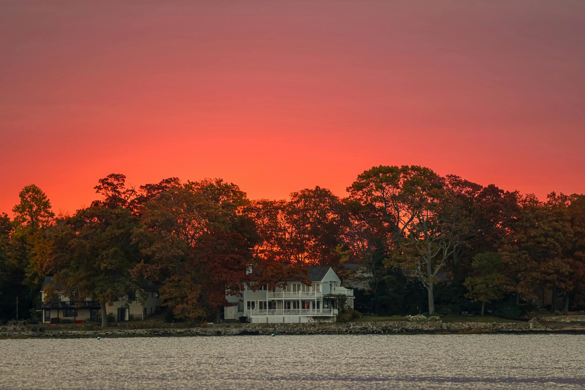 Capture the vibrant autumn sunrise over Stamford's waterfront, highlighting the fiery sky and tranquil atmosphere.